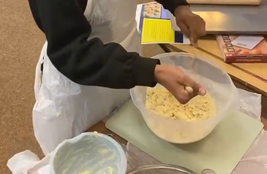 Hands rubbing butter into flour in a mixing bowl
