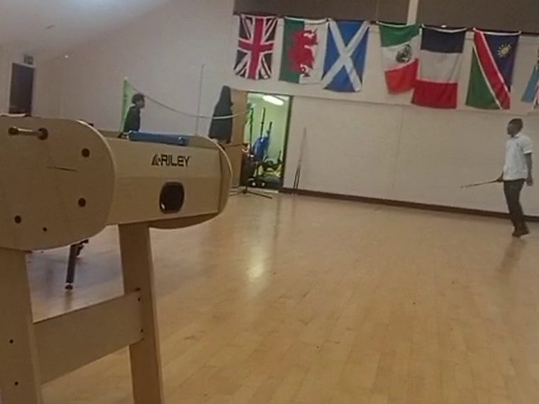 A student with a badminton racket in the school sports hall, vaulting horse in the foreground